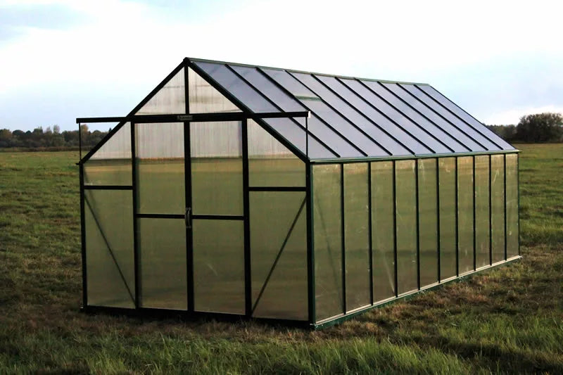 Greenhouse in a grassy field with a clear sky