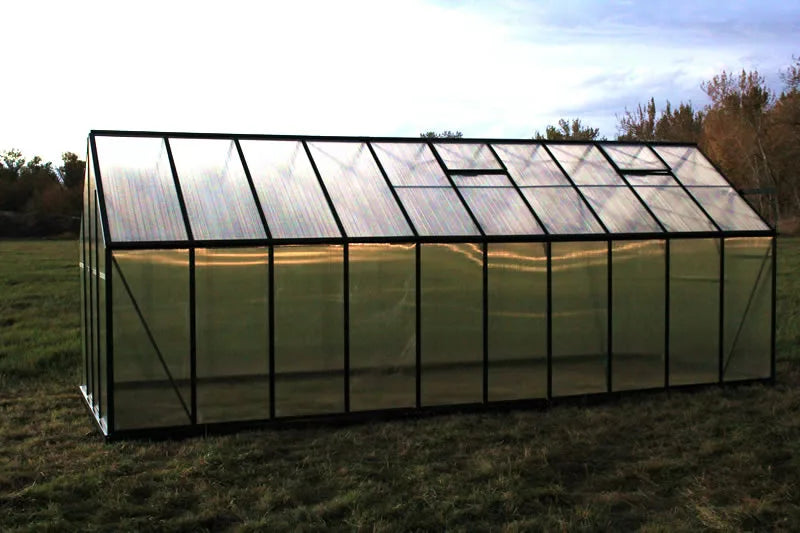 Greenhouse in a field with trees in the background side view