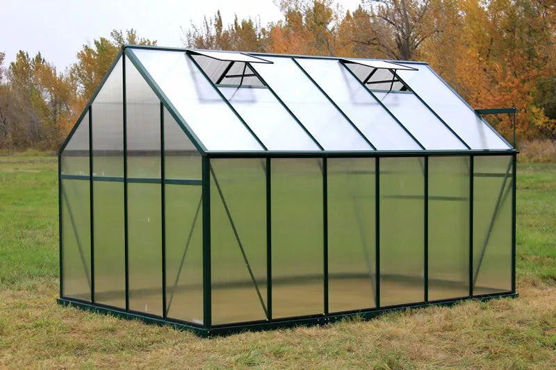Greenhouse in a grassy field with trees in the background